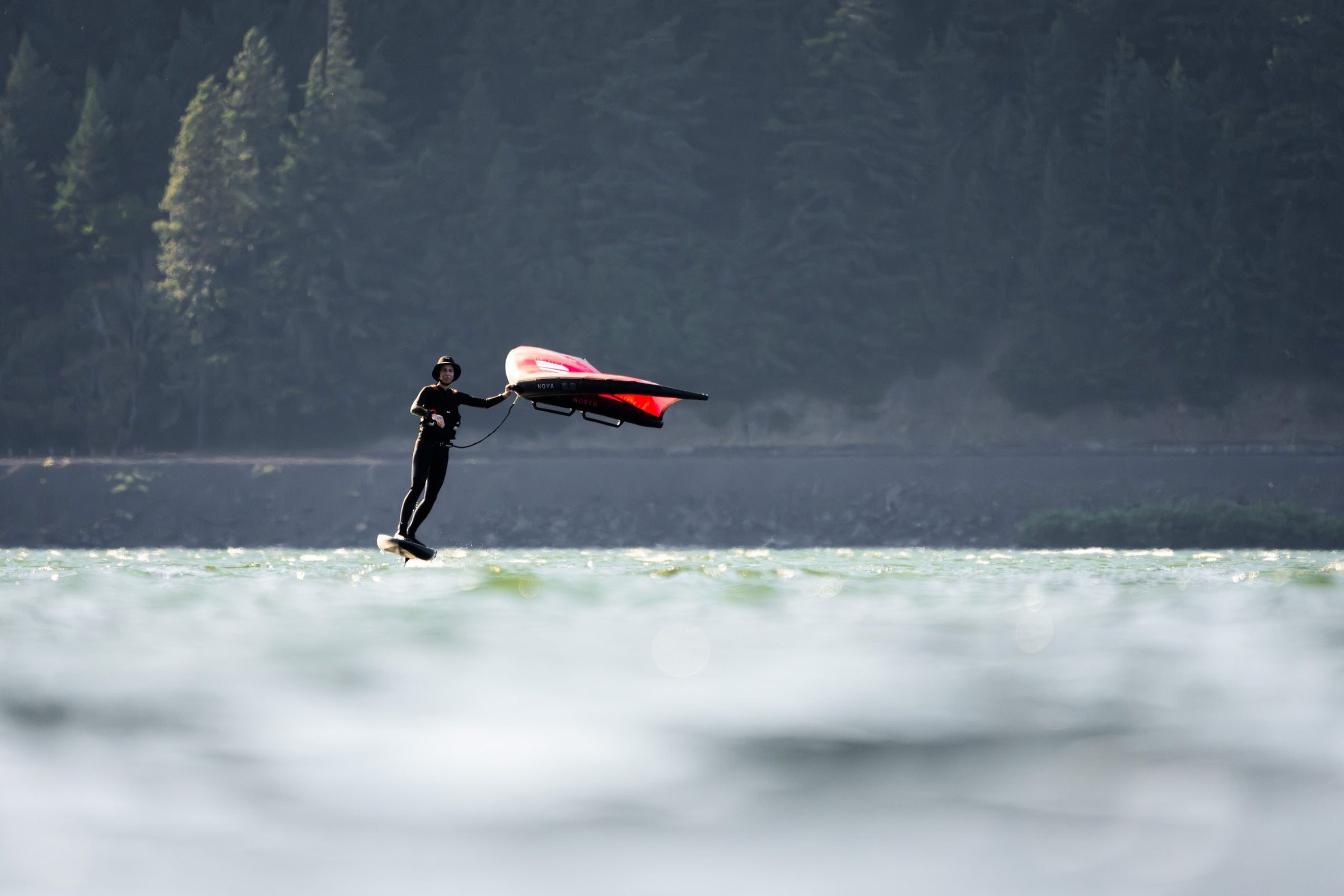 Wing foiling with a pink wing, wide backlit shot