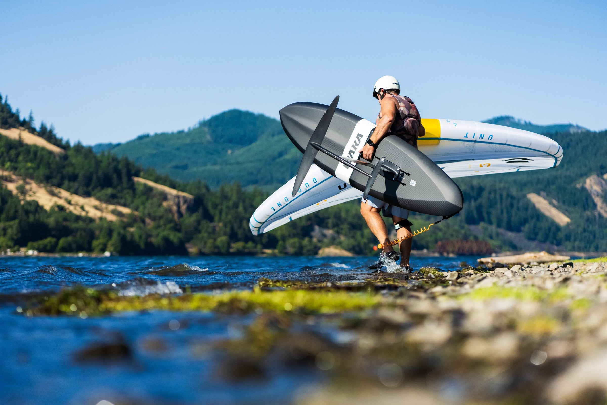 Rider carrying a WAKA board into the water, low angle