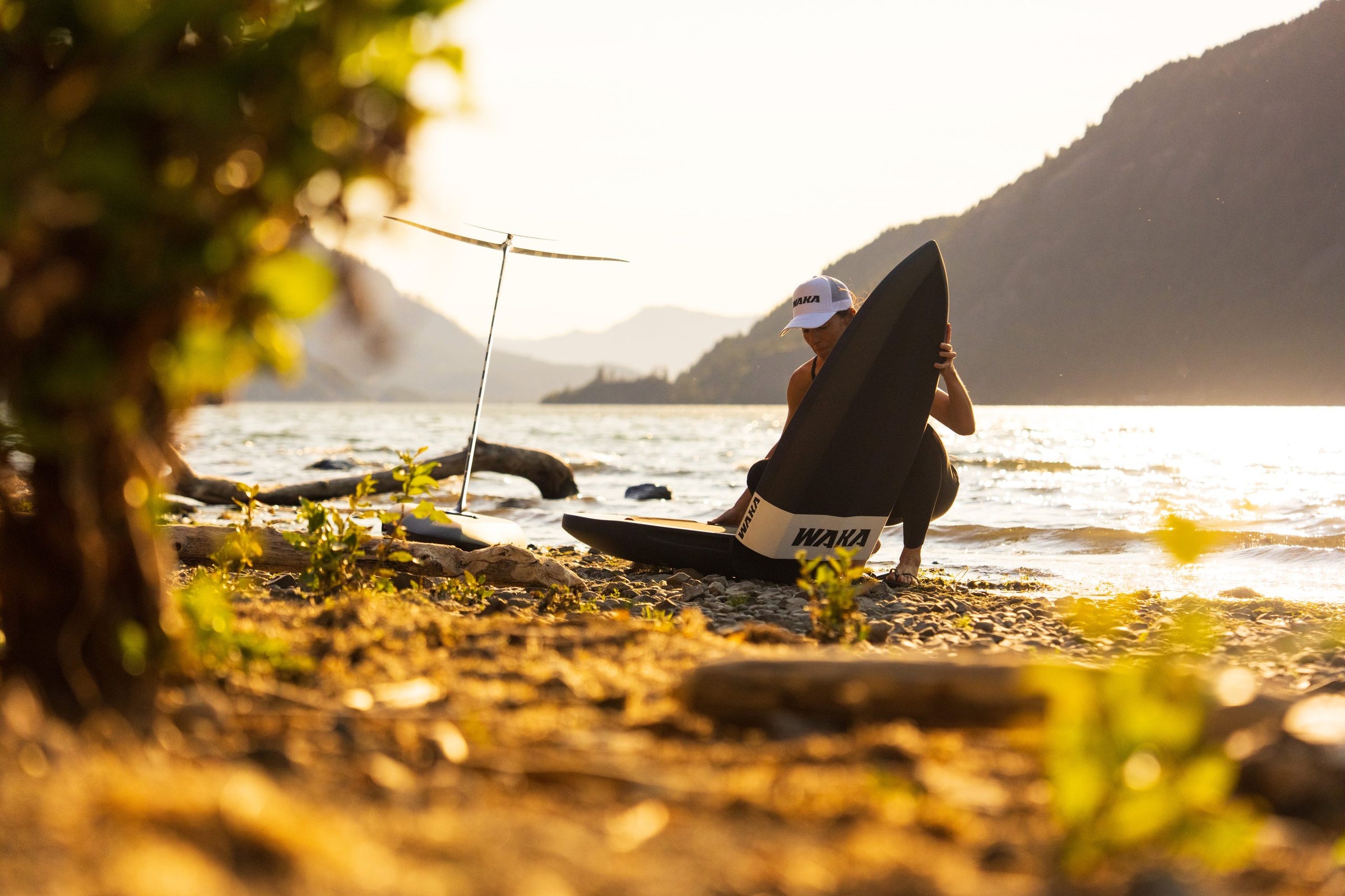 Rider folding a WAKA board, framed by foliage